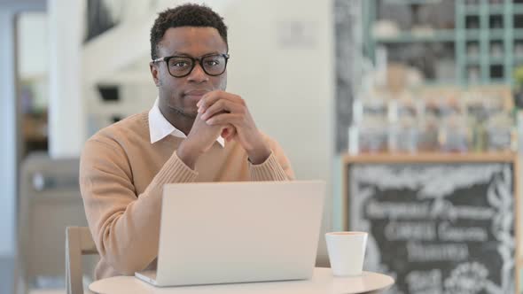 Creative African Man Looking at Camera While Working on Laptop