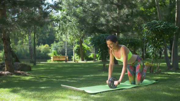 Smiling Fit Woman Working Out with Ab Roller in Park