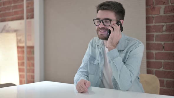 Happy Young Male Designer Talking on Smart Phone 