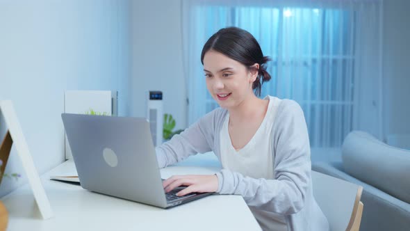 Distance learning of happy beautiful Business girl typing on laptop computer at night time in house