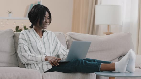 Relaxed Female Freelancer Sitting on Comfortable Sofa in Living Room Chatting Via Video Call on