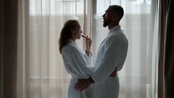 Lovers are Smoking Ecigarette in Hotel Room Man and Woman are Wearing White Robes