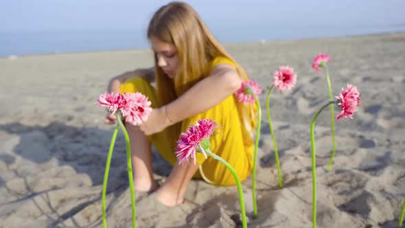 Girl Sitting with Flowers Planted in the Sand of the Beach