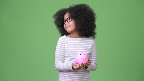 Young Cute African Girl with Afro Hair Holding Piggy Bank