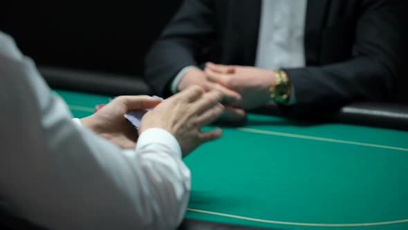 Male Croupier Shuffling and Dealing Cards at Casino, Player Checking Combination