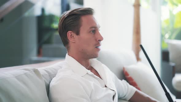 Tired Young Beautiful Man Sits on Armchair and Smoking Hookah in Slow Motion