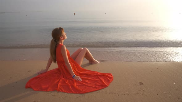 Young Happy Woman Wearing Red Dress Resting on Sea Beach Enjoying Warm Summer Morning