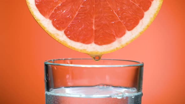 Closeup Juice Droplets Flowing in Glass From Grapefruit or Red Sicilian Orange