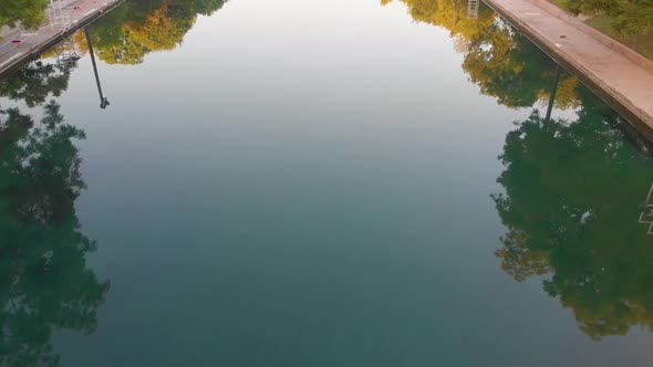 Top down shot of the crystal clear waters of barton springs pool. Slow pan up to downtown Austin Tex