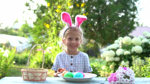 Little Girl with Bunny Ears Dyes Easter Eggs in Nature and Smiles a Child is Engaged in Creativity
