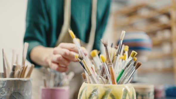 Close Up Shot of Female Artist Choosing Brush for Pottery Decoration Slow Motion