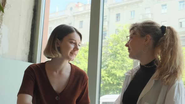 Young Girls Work Remotely in a Cafe on the Summer Terrace