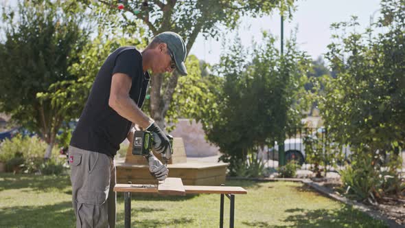 Slow motion of a man using an electric screwdriver to drive a screw into wood