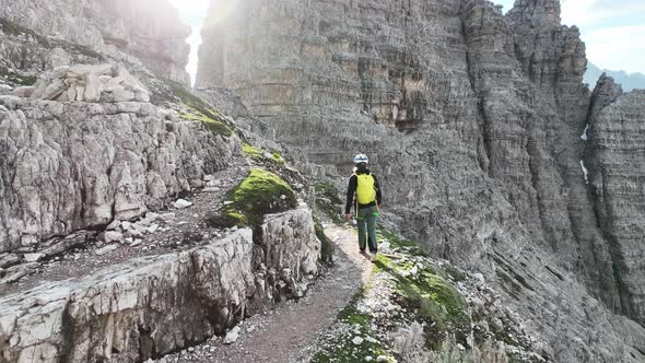 Female mountaineer with climbing gear in the Dolomites walking on a path.