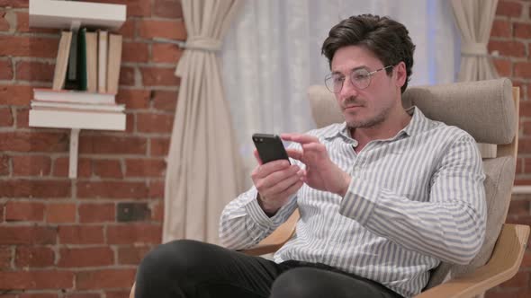 Middle Aged Man using Smartphone on Sofa