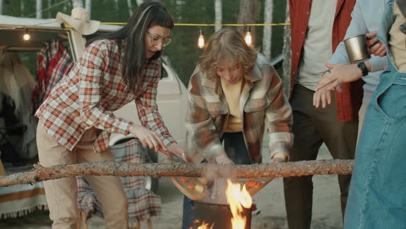 Young Tourists Cooking Food over Campfire