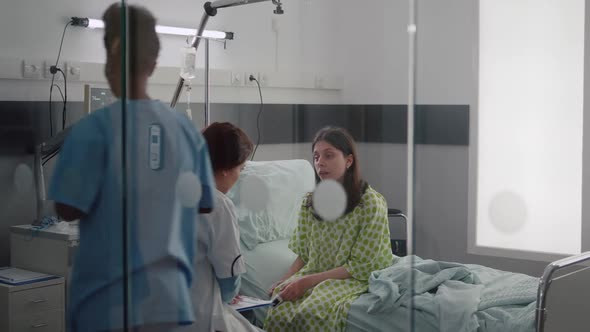 Sick Woman Talking with Doctors While Sitting on Bed During Sickness Recovery