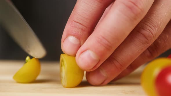 Professional Chef Cutting Cherry Tomato on Wooden Cutting Board Closeup