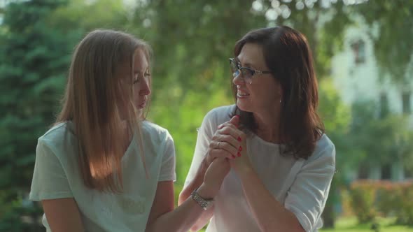 Smiling Happy Caucasian Senior Mother with Her Adult Daughter Hugging and Laughing In Park. Concept