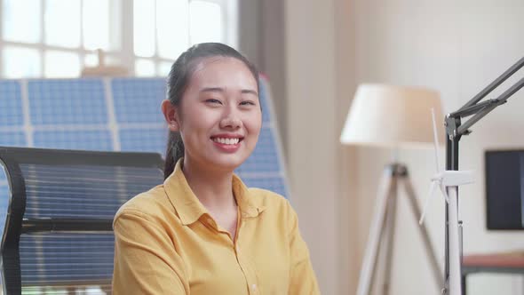 Asian Woman Look At Wind Turbine , Cross Arms, And Smile To Camera While Working With Laptop