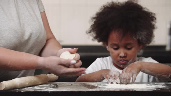 Black Little Girl with Her Mother Making Dough  the Girl Playing with the Flour