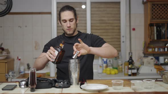 Young Barman Using Jigger to Put Alcohol on Cocktail Shaker in Traditional Spanish Kitchen