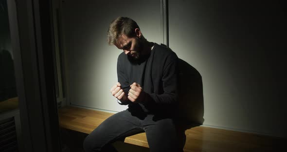 Man Sitting In A Prison Cell In Handcuffs