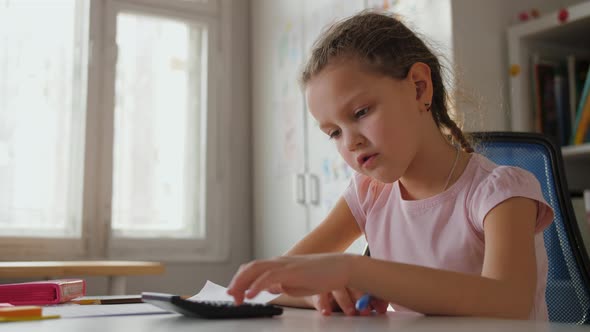 Cute Primary School Girl Doing Homework Lesson Counting on Calculator