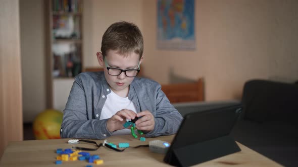 Boy with Effort Assembles His Own Model of Robot Attaches an Electronic Cable