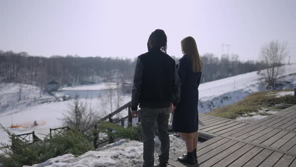 Wide Shot of Happy African American Man and Caucasian Woman Holding Hands Standing on Sunny Hotel