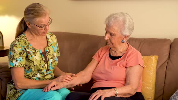 Home healthcare therapist helping elderly woman with arm stretches.