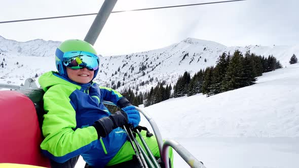 Skier Boy on the Chair Lift Put Hands Up and Smile