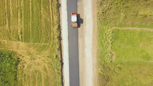 Aerial view of new road construction with steam roller machine at work.