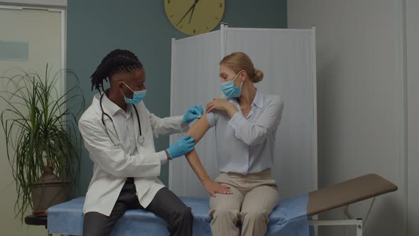 Male Doctor or Nurse Making Vaccine Injection to Patient Indoors