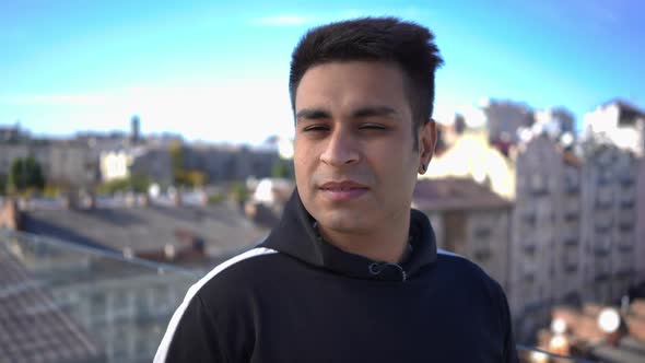 Closeup Portrait of Young Middle Eastern Man Standing in Sunbeam on Rooftop Looking at Camera and