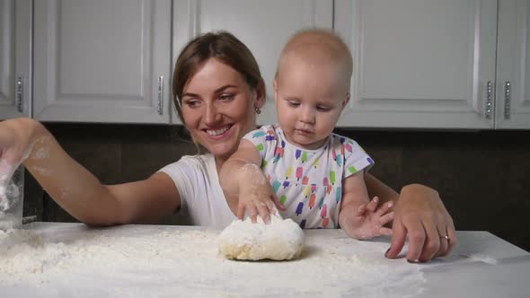 Young Mother and Her Little Daughter Preparing Dough on the Table