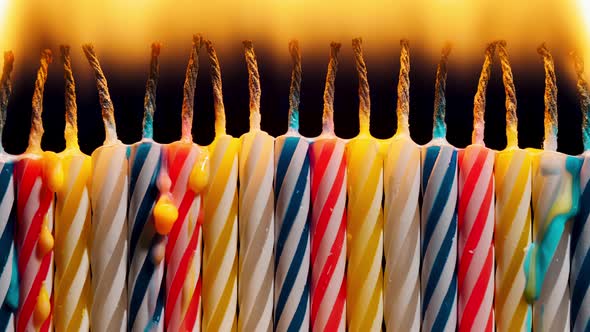 Closeup Set of Colorful Birthday Candles Burning in Timelapse on Black Background
