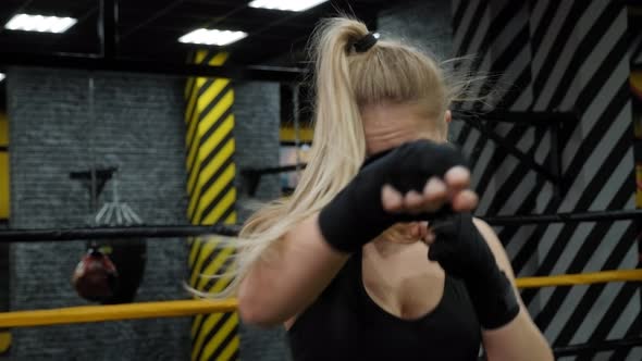 A Sporty Woman with Long Hair Practices Punches in a Boxing Gym