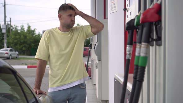 A Man Fills Up a Car with Gasoline and is Angry at the High Prices