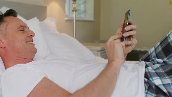 Man using mobile phone while relaxing on bed