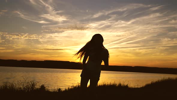 Free and Cheerful Woman, Happy Girl with Long Hair Is Dancing at Sunset on the Beach and Laughing