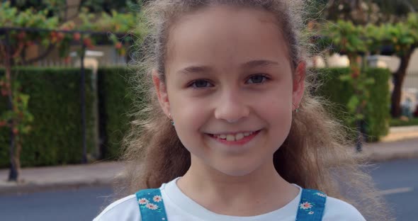 Portrait Cute Little Child Girl Looking at Camera Standing on Street in City on Summer Day