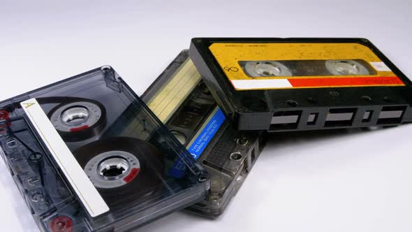 Three Vintage Audio Cassettes Rotate on White Background