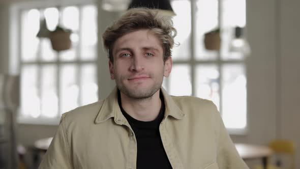 Portrait of Young Man with Trendy Haircut Posing at Cafe