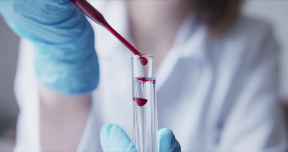 Scientist with Pipette Analyzes Red Colored Liquid To Extract the DNA