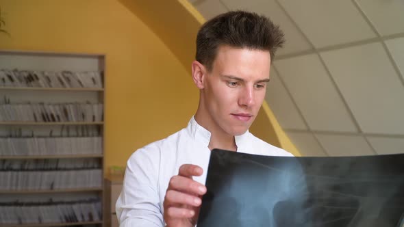 Young Doctor Examines X-ray of Lungs in Clinic. Doctor Examines X-ray of Lungs of a Patient with