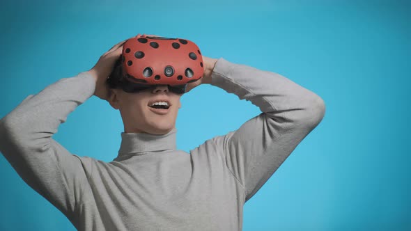 Emotional Guy with VR Glasses Clutches Head Playing on Blue