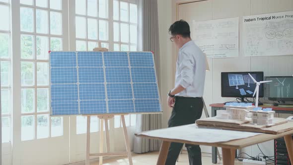Asian Man Walks Into Looking The Solar Cell In The Room That Has Model Solar Panel Small House