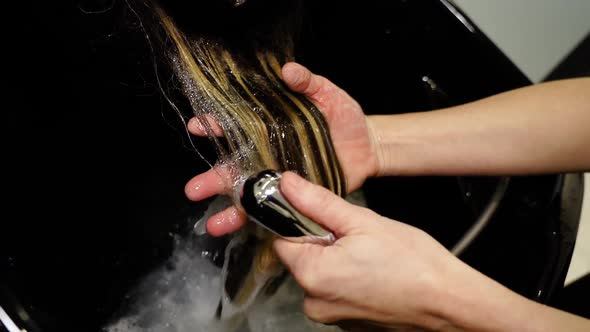 Hairdresser Washes Woman Highlighted Hair with Running Water