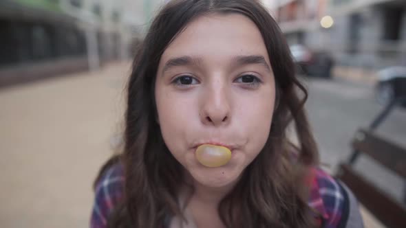 Closeup Face of Brunette Caucasian Teenage Girl with Brown Eyes Puffing Gum Smiling Looking at